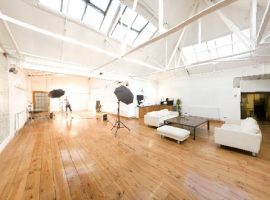 A photo of a bright, airy studio with large windows and a wood floor